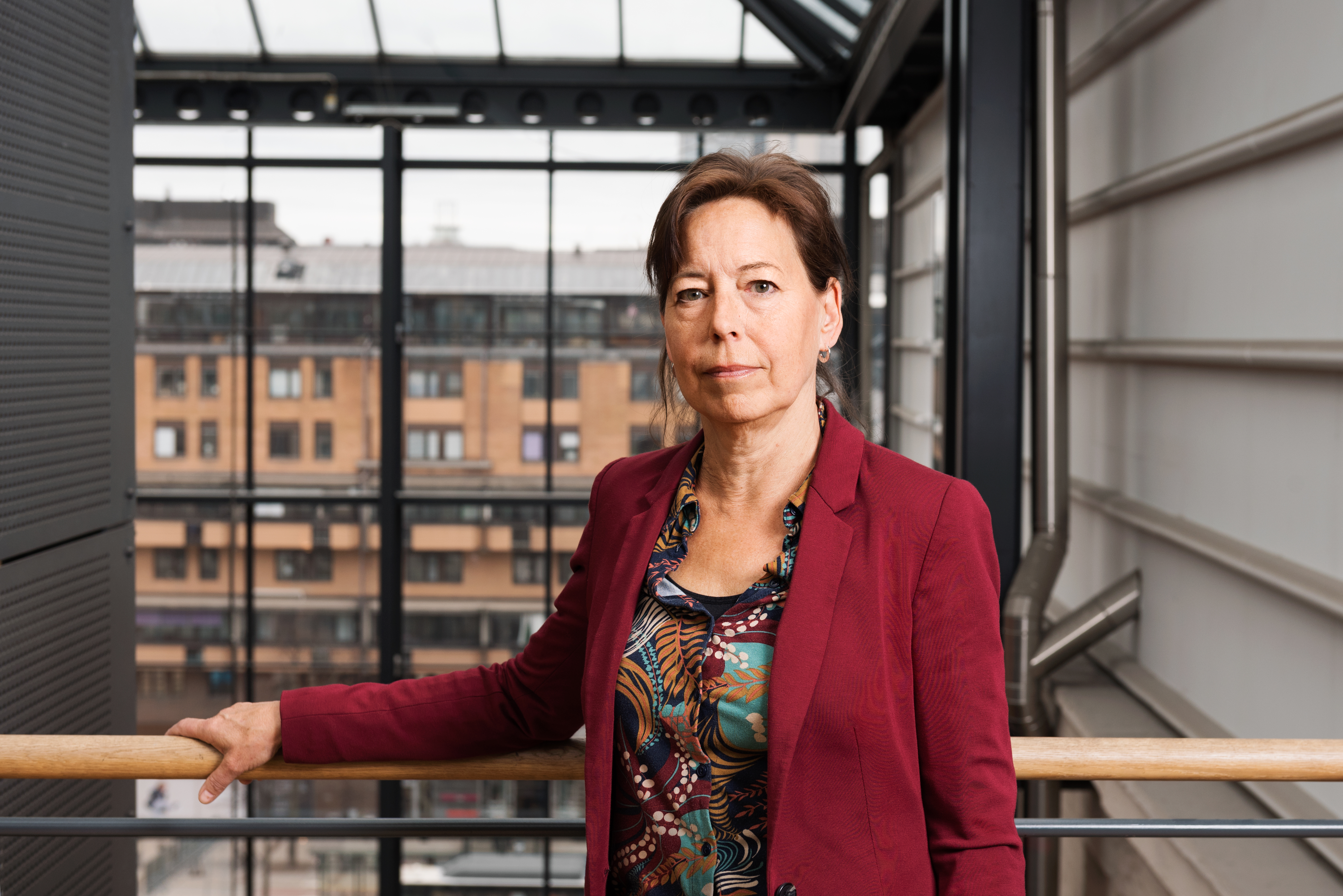  Anna-Karin Lindblom står framför ett fönster och tittar in i kameran. Hon ser allvarlig ut.