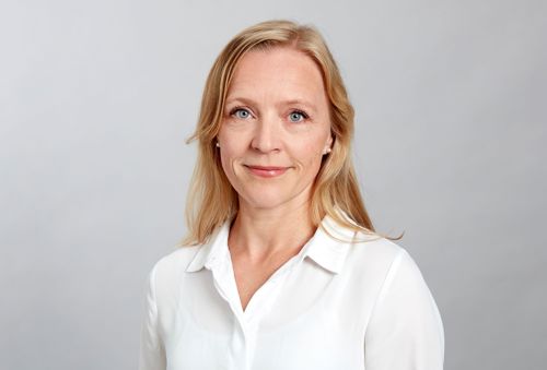 Porträttbild Pia Brundin. Pia har ljust halvlångt hår och en vit skjorta. Hon tittar in i kameran och ler vagt.