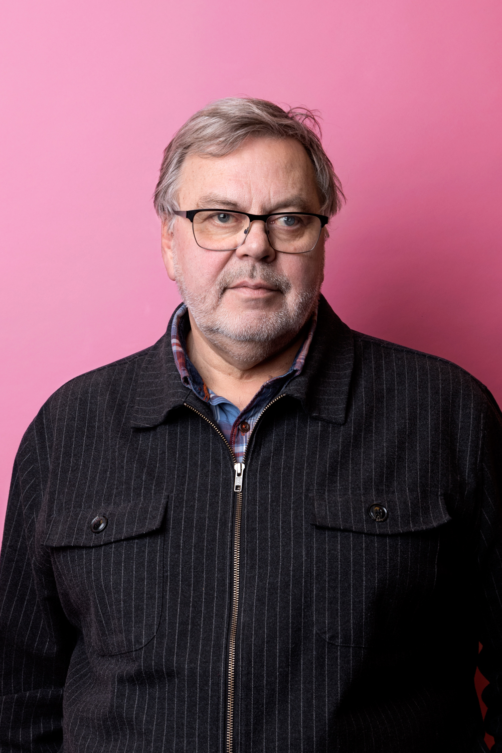 Porträttbild av Mats Bernerstedt. Mats har kritsstrecksrandig tröja över en rutig skjorta.