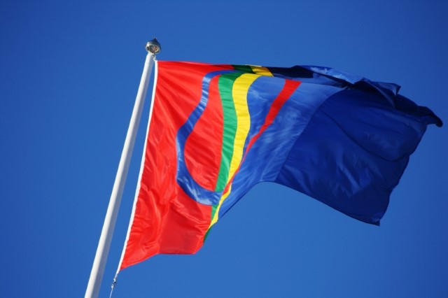 En bild på samiska flaggan som vajar mot en blå himmel