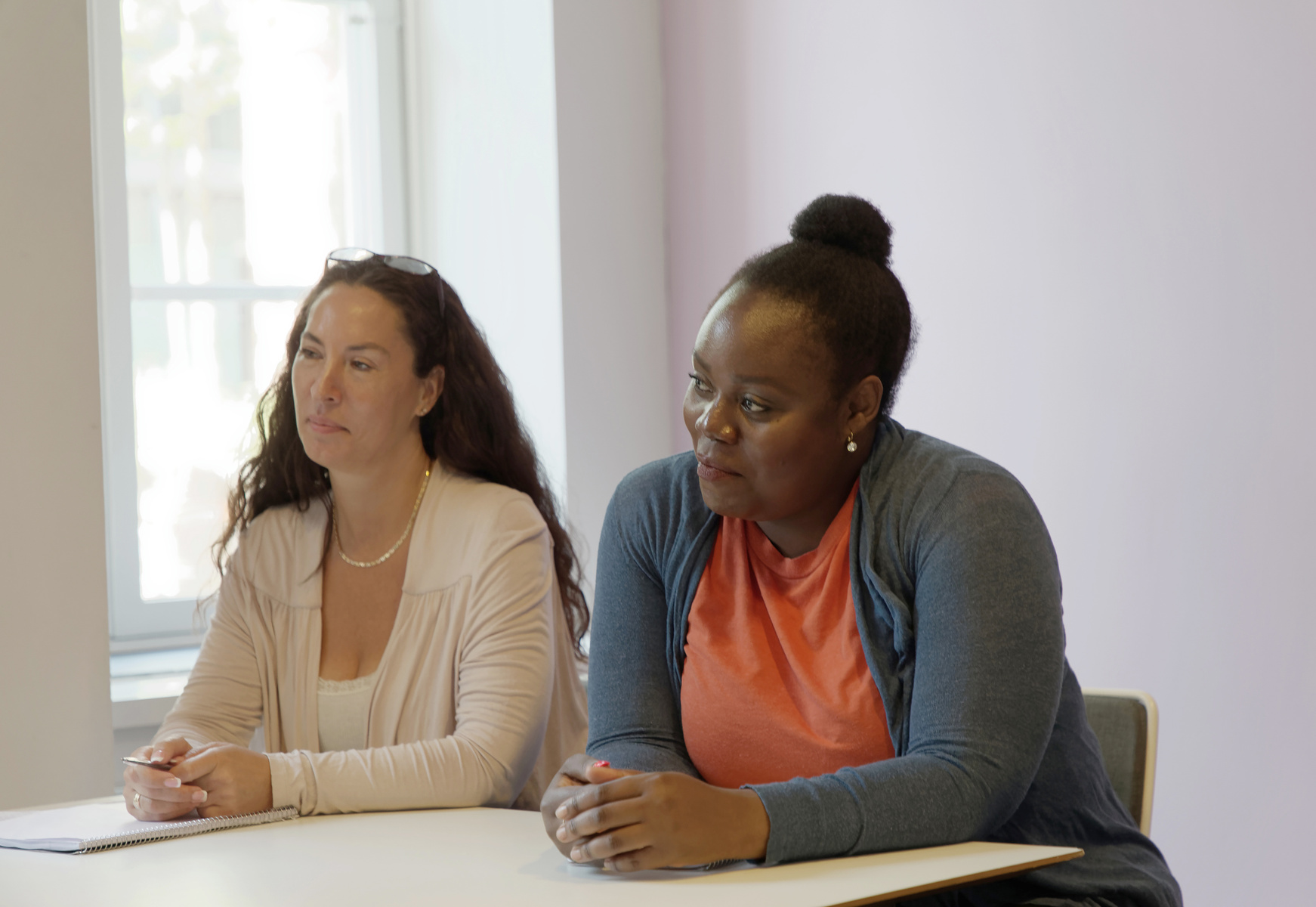 Två kvinnliga studenter sitter i skolbänken i ett klassrum.