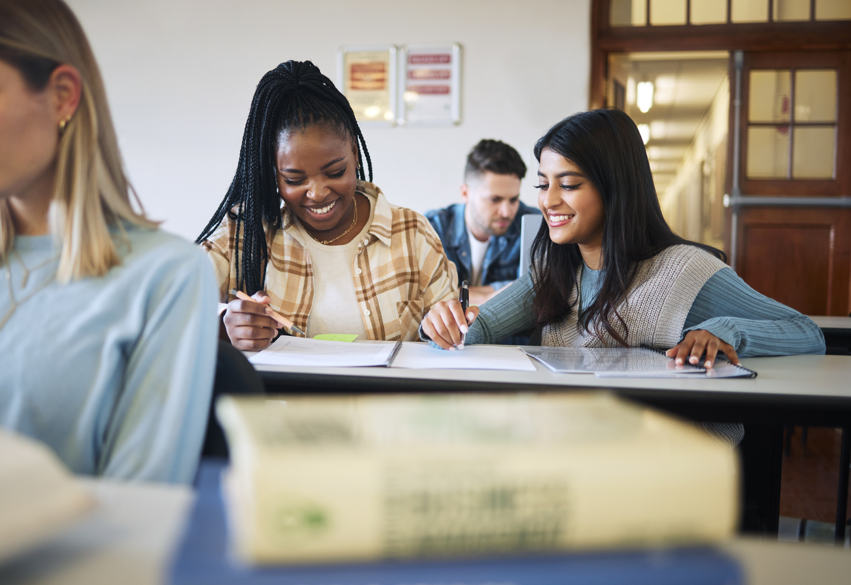 Två unga kvinnor sitter i ett klassrum och arbetar med gemensam uppgift.