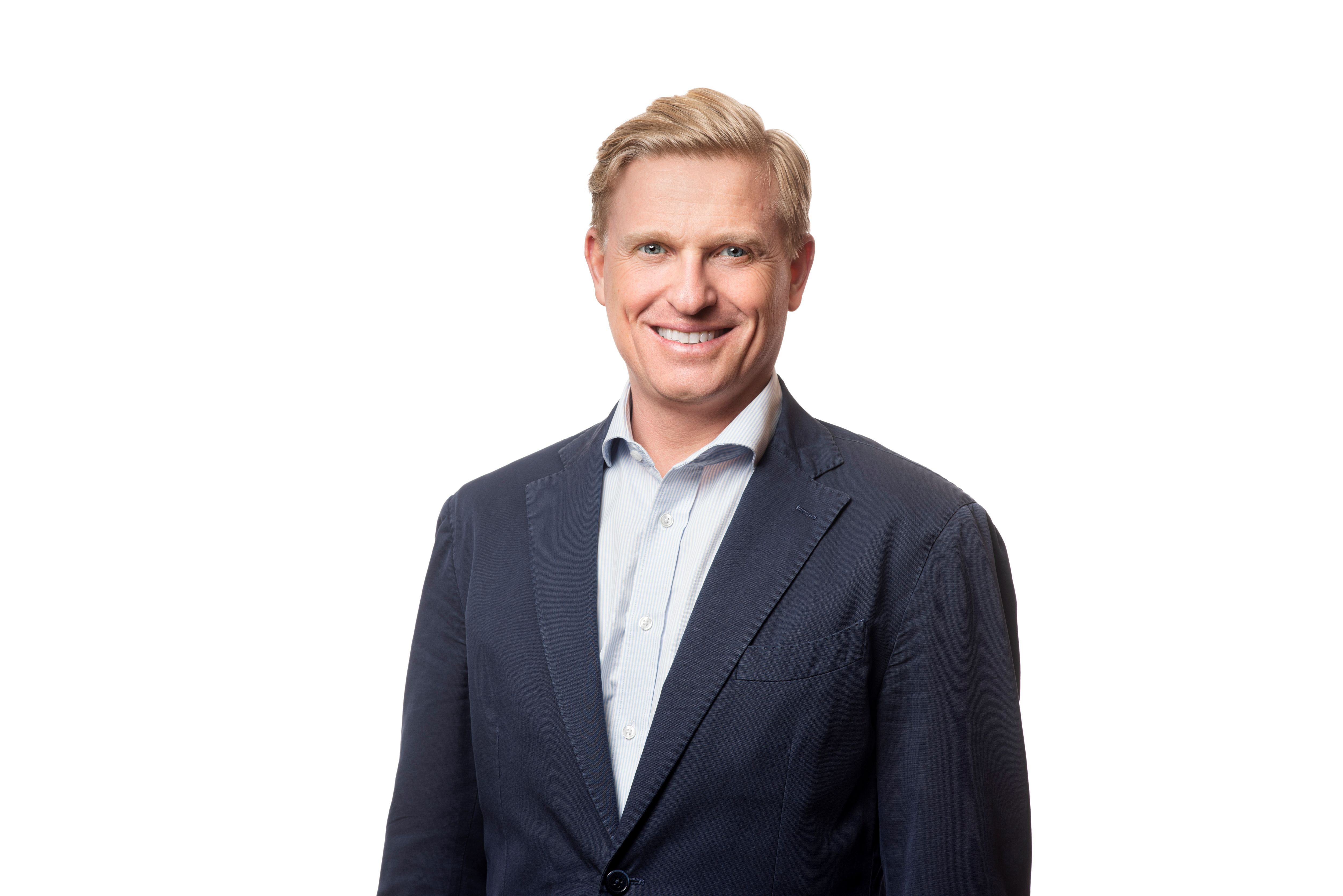 Porträttfoto av en leende Gustav Blix i kavaj mot vit bakgrund.