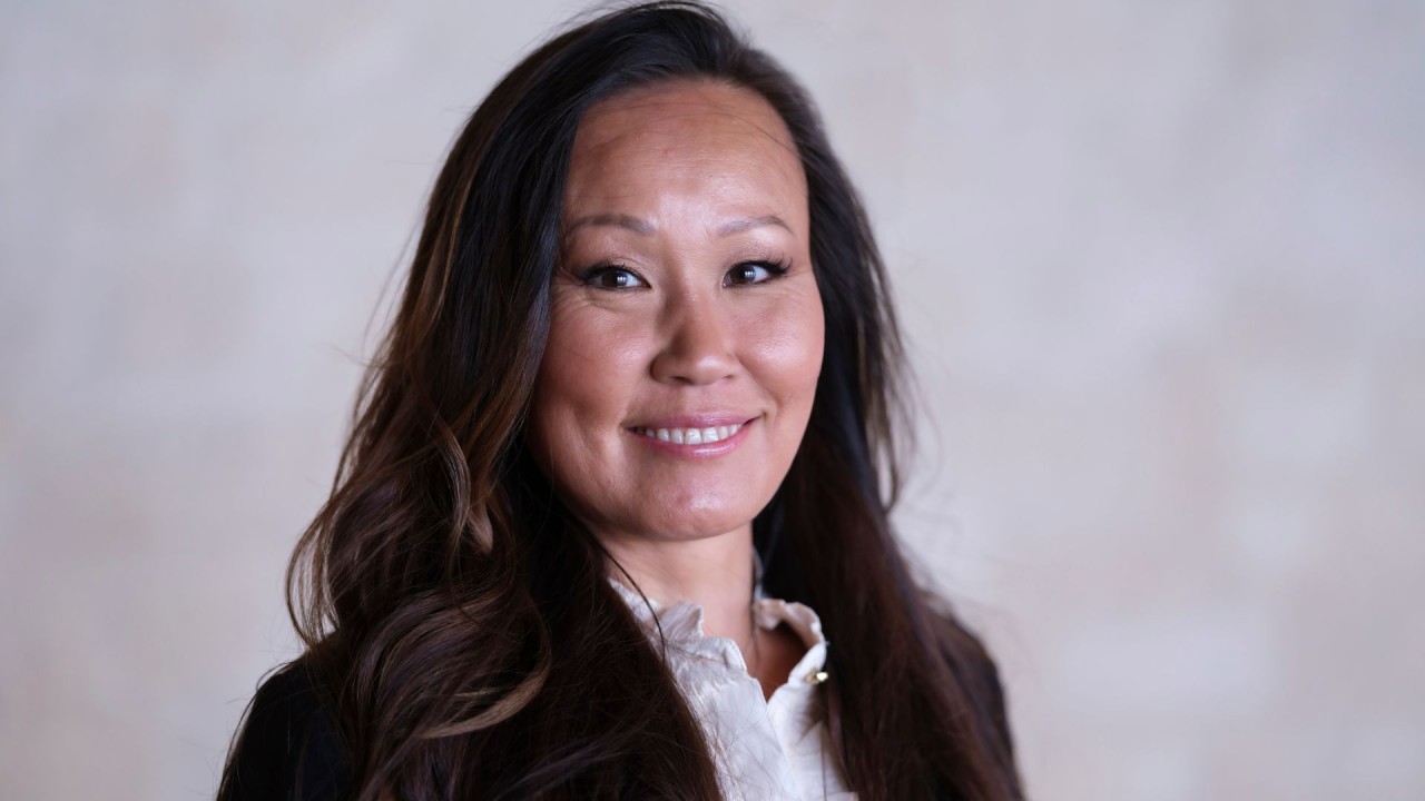 Jiang har långt mörkt hår, tittar mot kameran med ett leende.