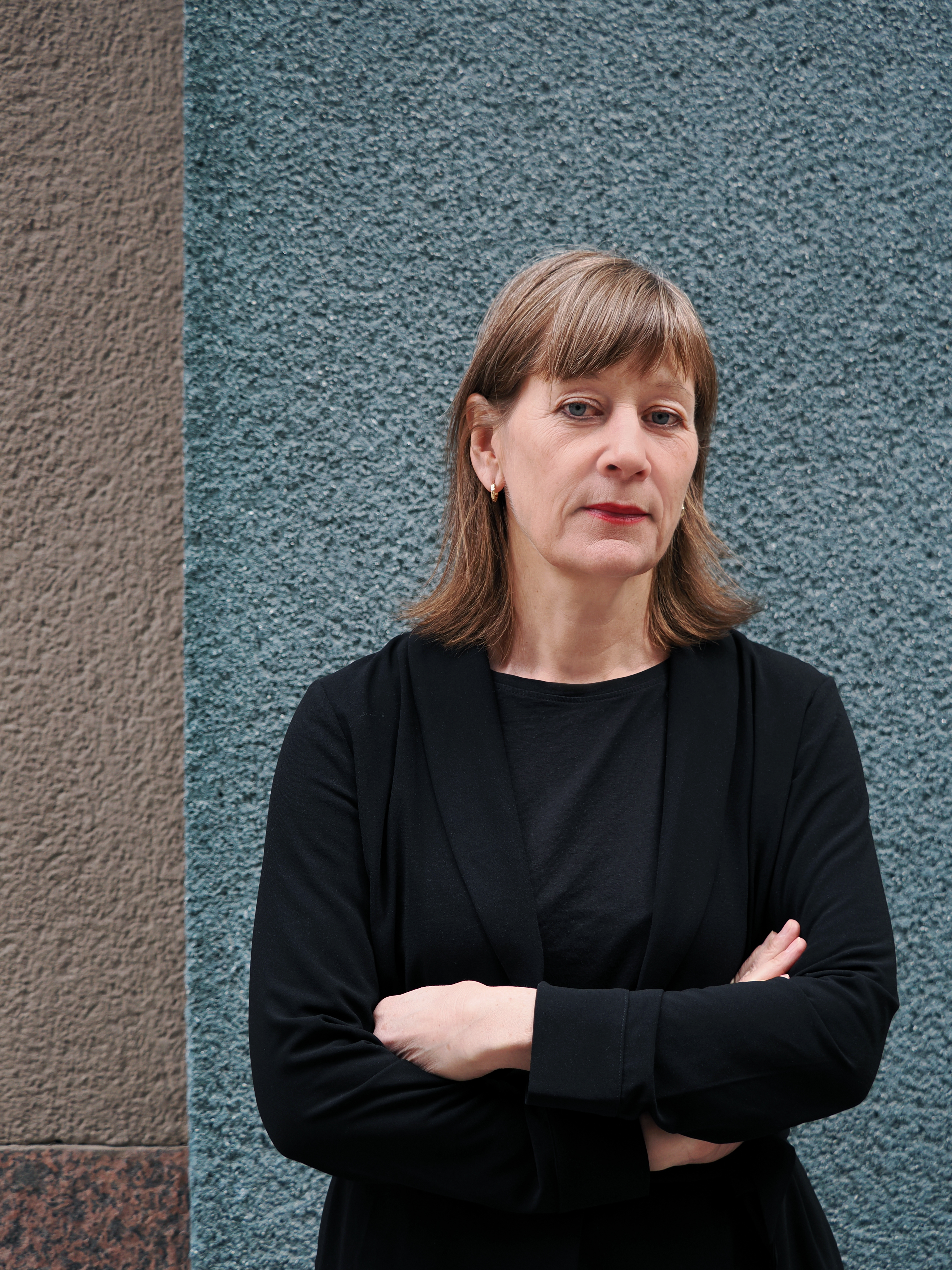 Silvia Ernhagen generalsekreterare för Svenska biblioteksföreningen står framför en turkos vägg, hon ser bistert in i kameran.