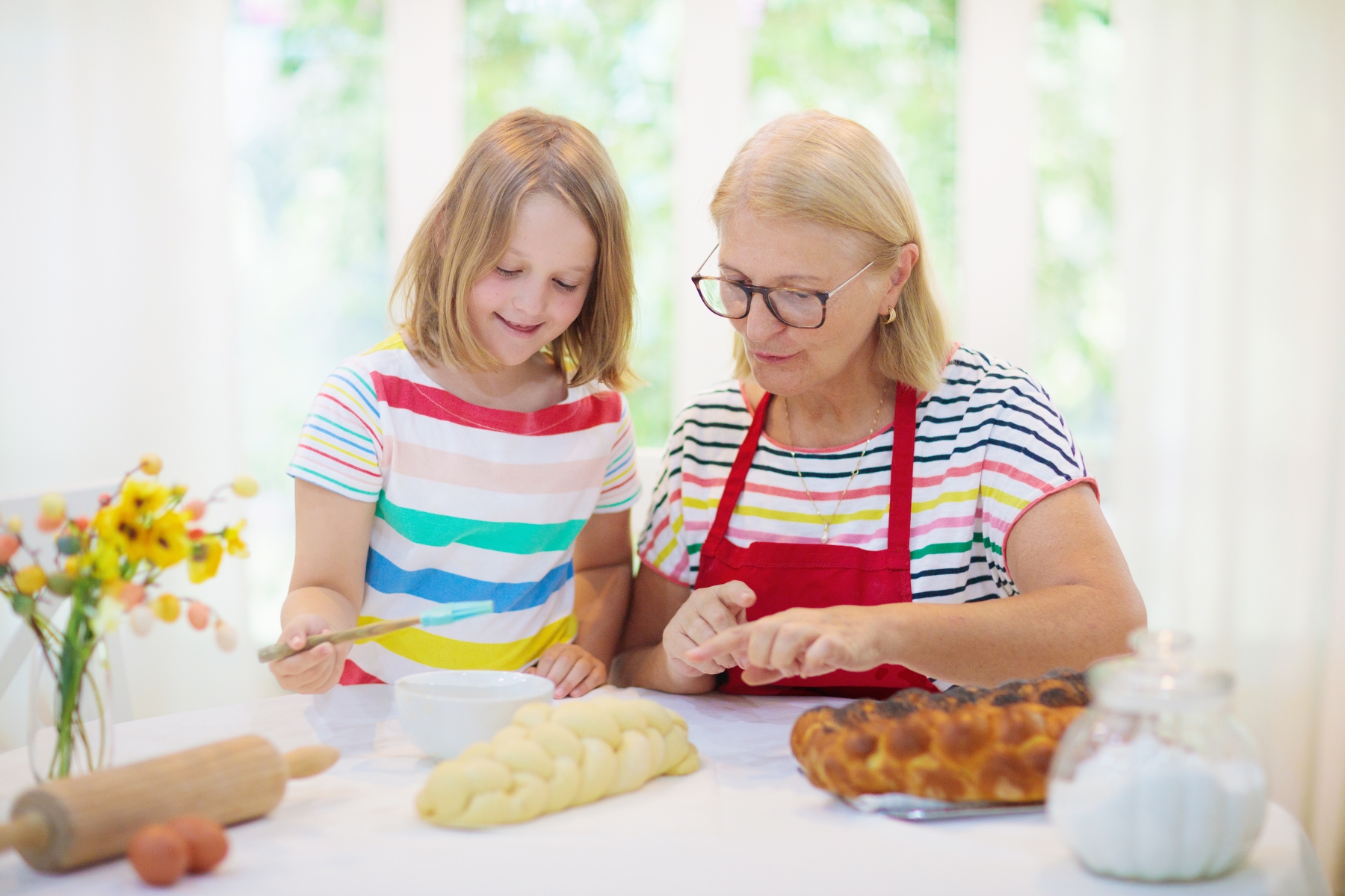 Ett barn och en äldre kvinna bakar traditionellt judiskt bröd tillsammans.