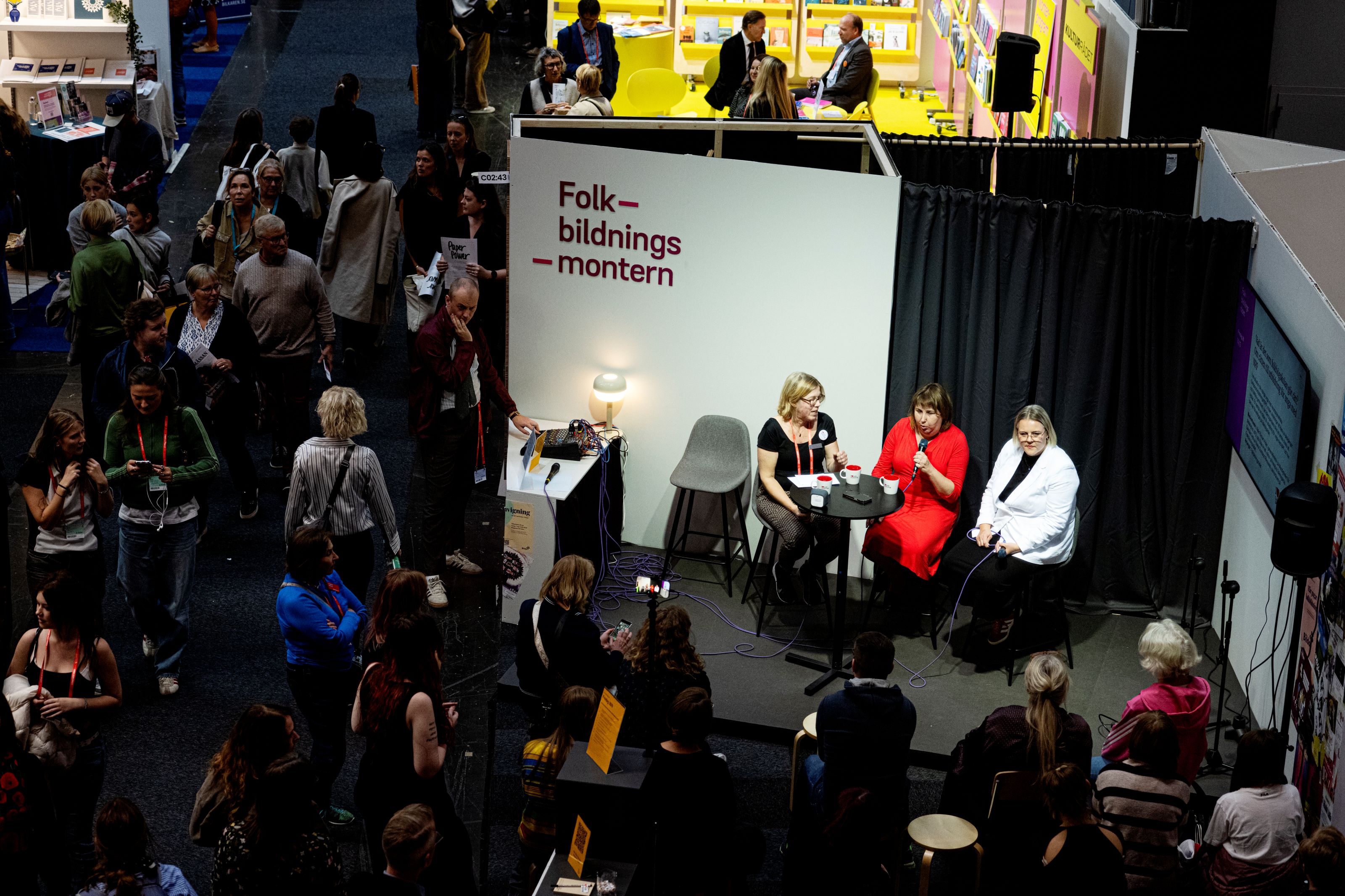 Folkbildningsmonten fotad ovanifrån. Panelsamtal pågår på scenen under ledning av Folkbildningsrådets Maria Sundbom Ressaissi. 